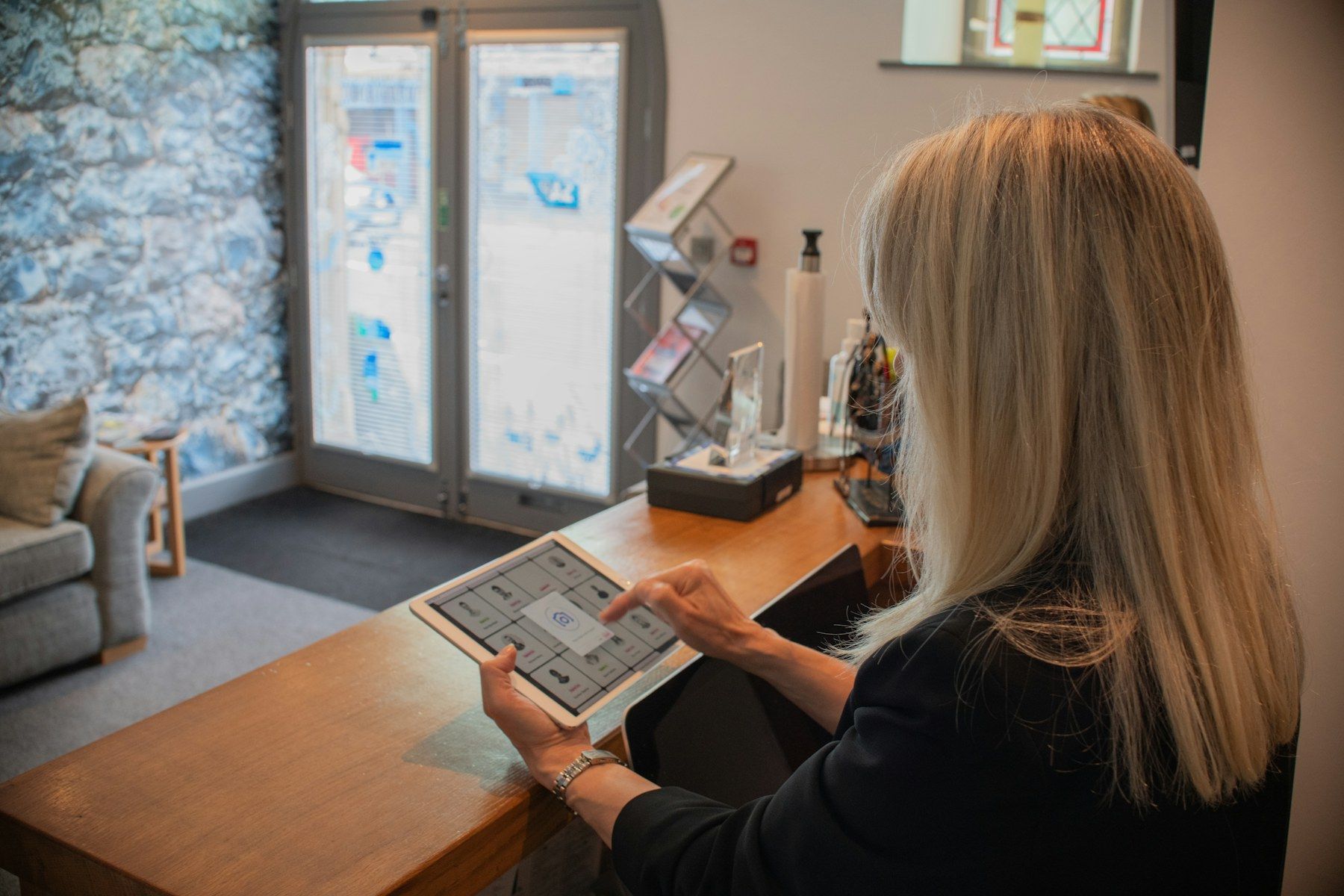 Receptionist using a tablet at the front desk of a small office