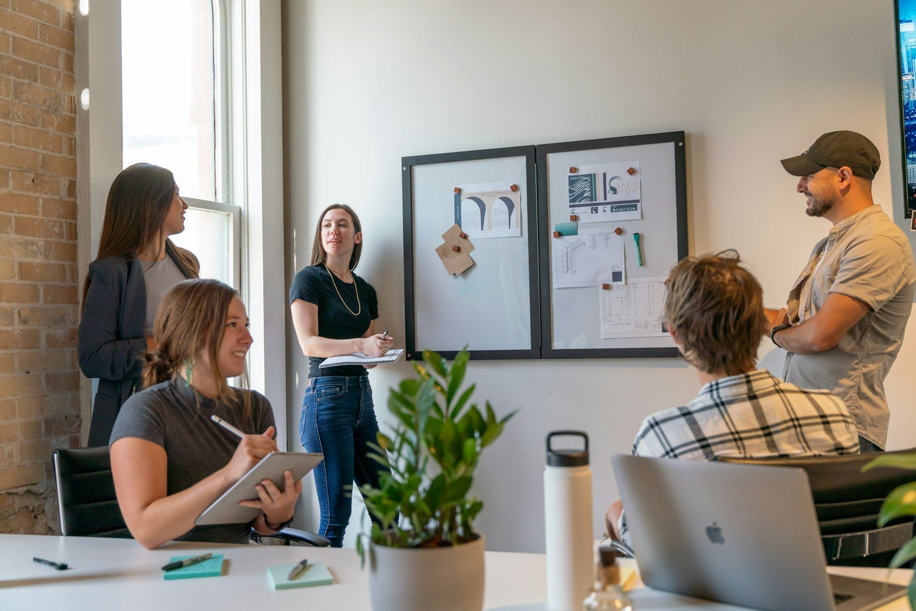 Small team meeting in a sunlit office, with one person leading the discussion